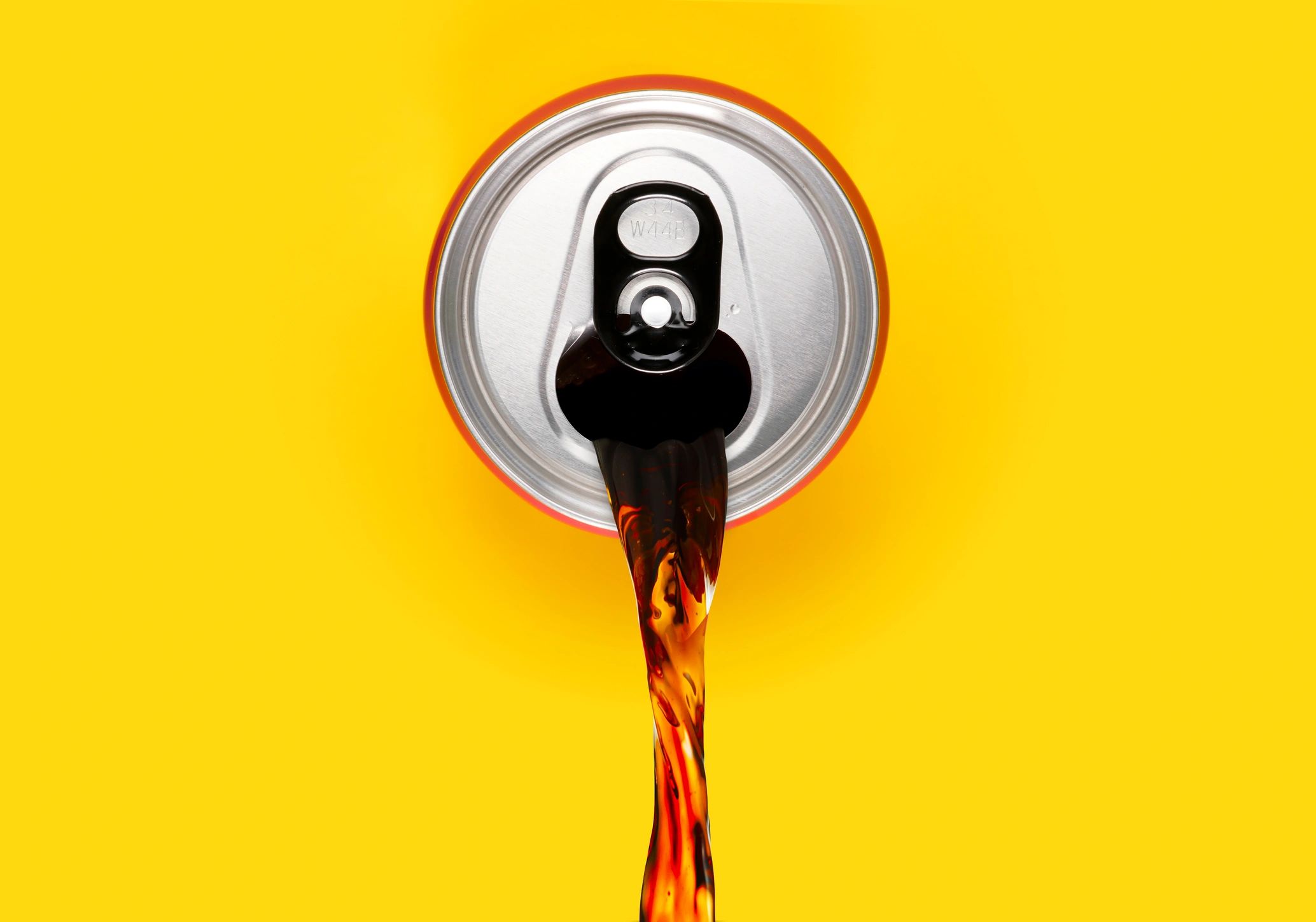 Beverage can pouring liquid on a bright background